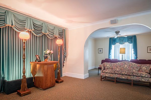 Funeral home interior with reception desk, seating area, and blue curtains.