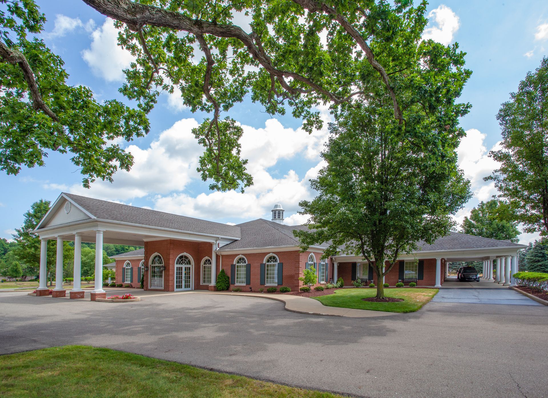 The front door of a house with a porch and plants in front of it.