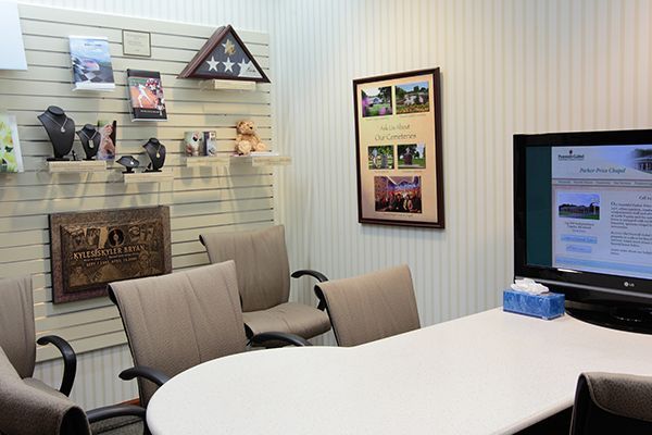 Conference room with chairs, table, display of items, and a TV screen.
