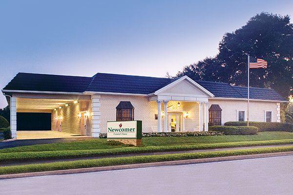 Funeral home with a covered entrance, sign, and American flag.
