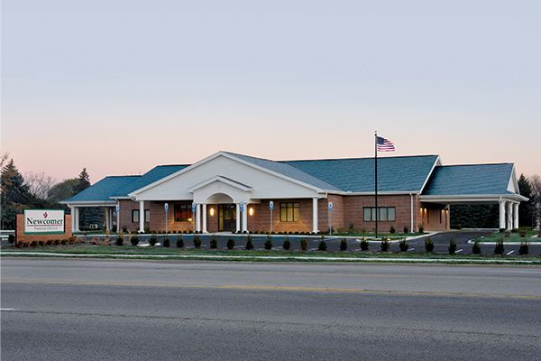 Brick building with a sign and American flag, viewed from the street.