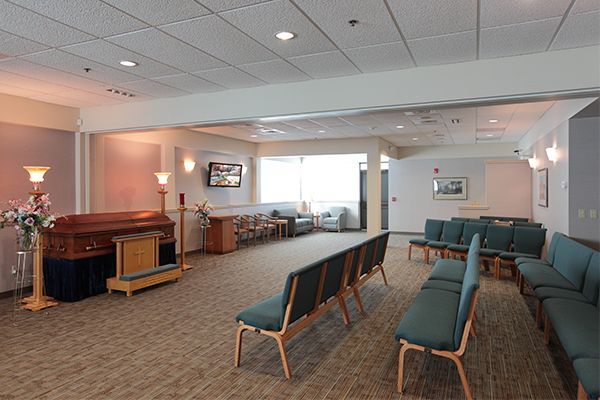 Interior of a funeral home with a casket, seating, and a window.