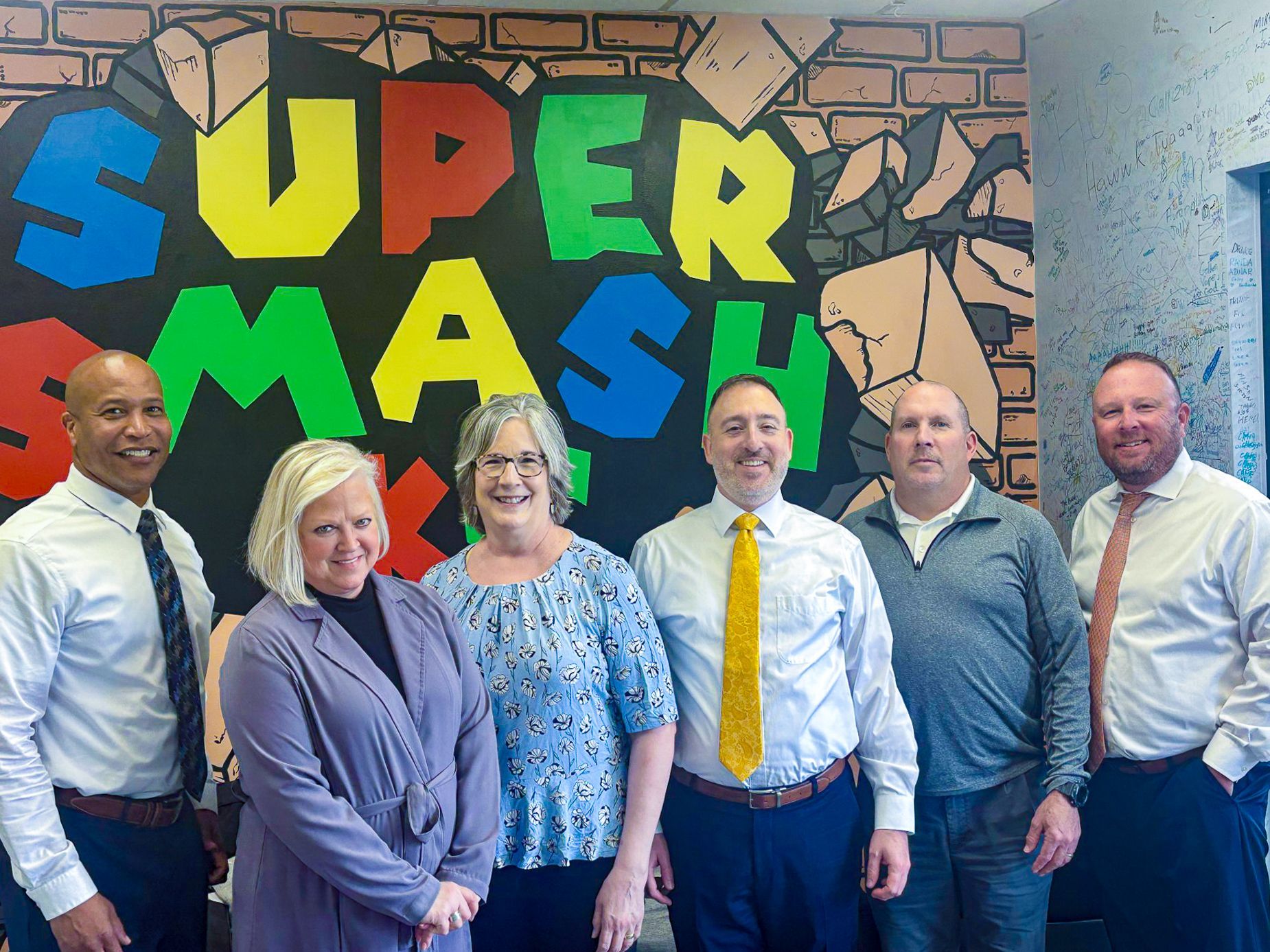 Brick building with white columns, arched windows, and a porte-cochère under a blue sky.