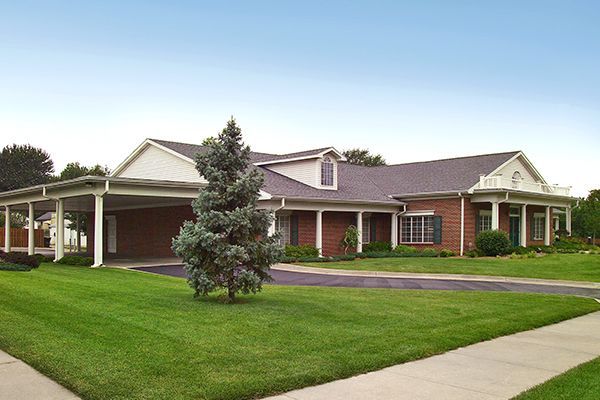 Brick building with covered entrance, green lawn, and blue sky.