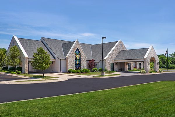 Stone church building with dark roof, blue sky, and green lawn.