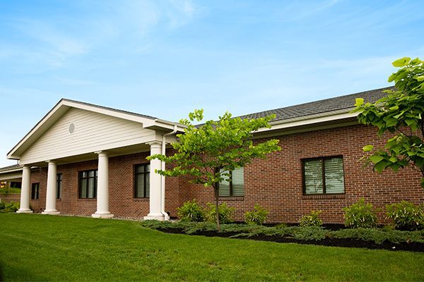 Brick building with white pillars, green lawn, and blue sky.