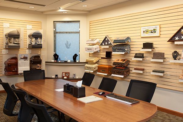 Meeting room with a long table, displays of urns on the wall, and chairs.