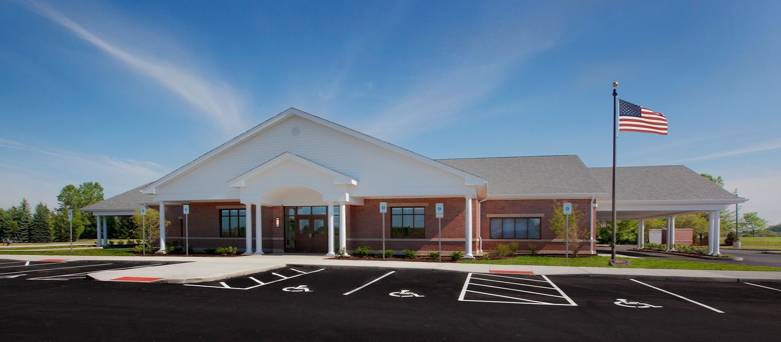Brick building with white trim, American flag waving, and a blue sky.