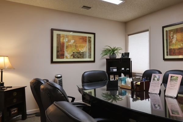 Conference room with black leather chairs, a shiny table, and artwork on the walls.