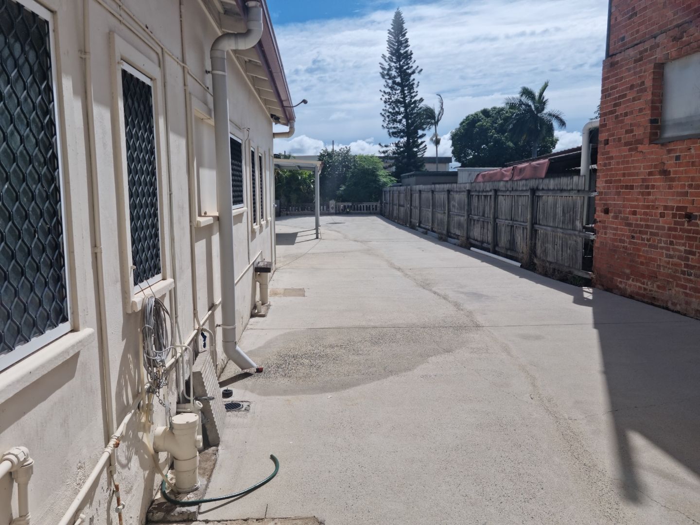 A Woman is Using a Pressure Washer to Clean a Driveway — Blast H2O In Collinsville, QLD