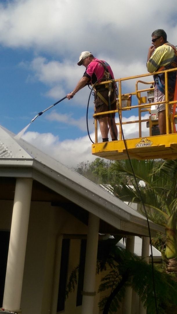 A Man is Cleaning the Roof of a House With a High Pressure Washer — Blast H2O In Proserpine, QLD