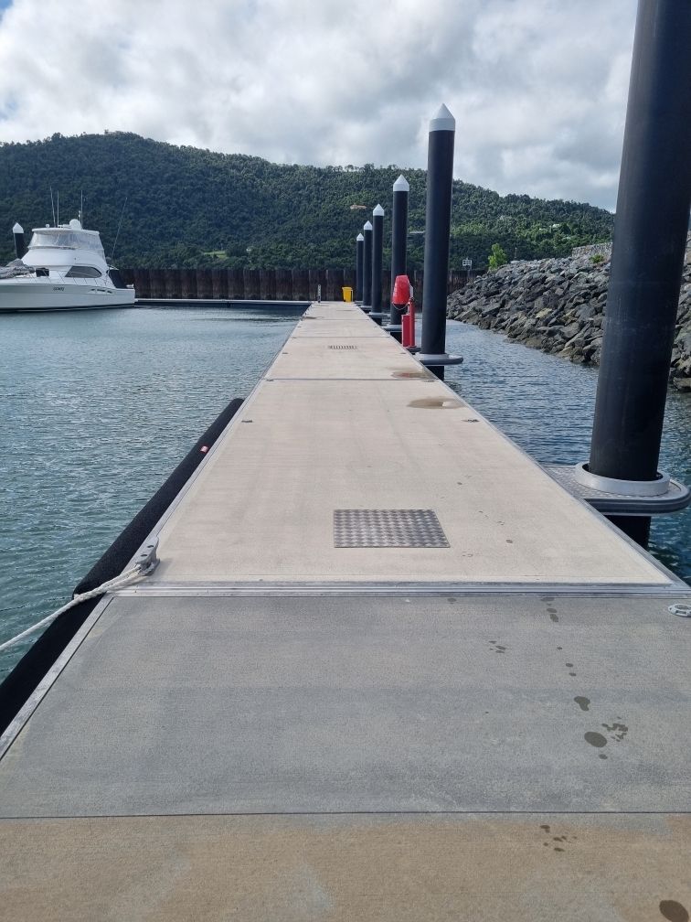 A Man is Cleaning a Wooden Deck With a High Pressure Washer — Blast H2O In Bowen, QLD