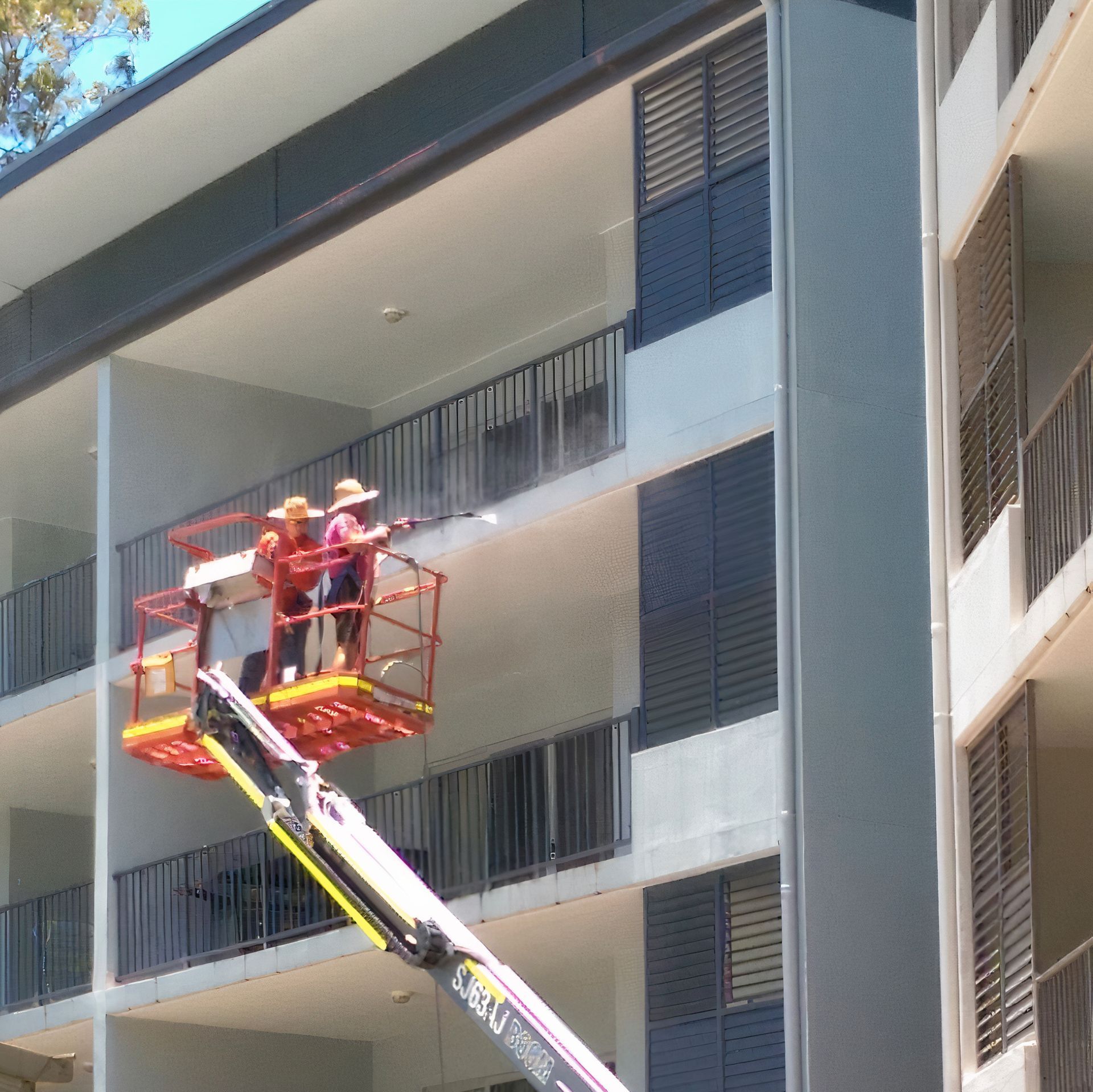 A Man is Standing on a Lift in Front of a Building — Blast H2O In Cannonvale, QLD