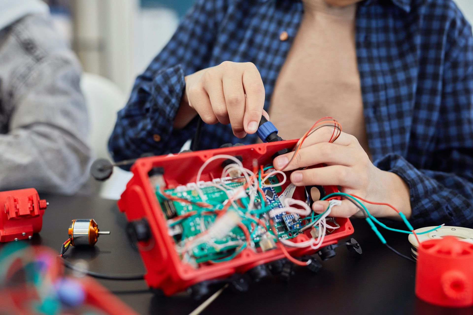 A person is sitting at a table working on a robot.