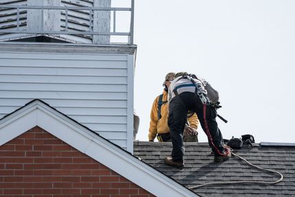 Two Men Are Working on the Roof of a Building — East Coast Roof Tiling Services in Kuluin, QLD