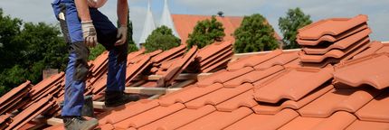 A Man is Standing on Top of a Tiled Roof — East Coast Roof Tiling Services in Kuluin, QLD