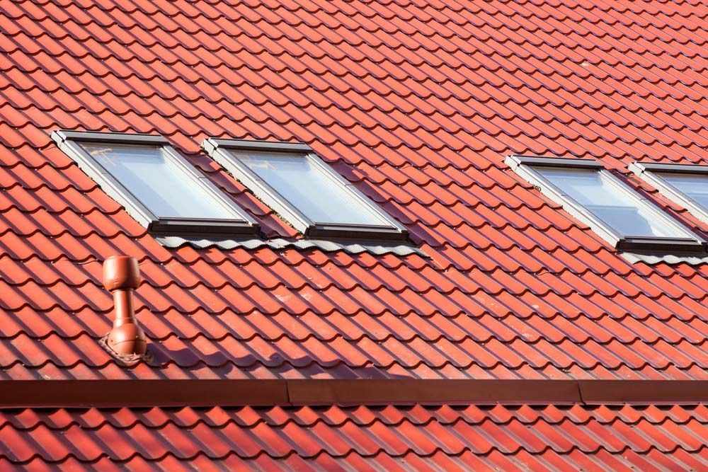A Red Tiled Roof With Three Skylights on It — East Coast Roof Tiling Services in Kuluin, QLD