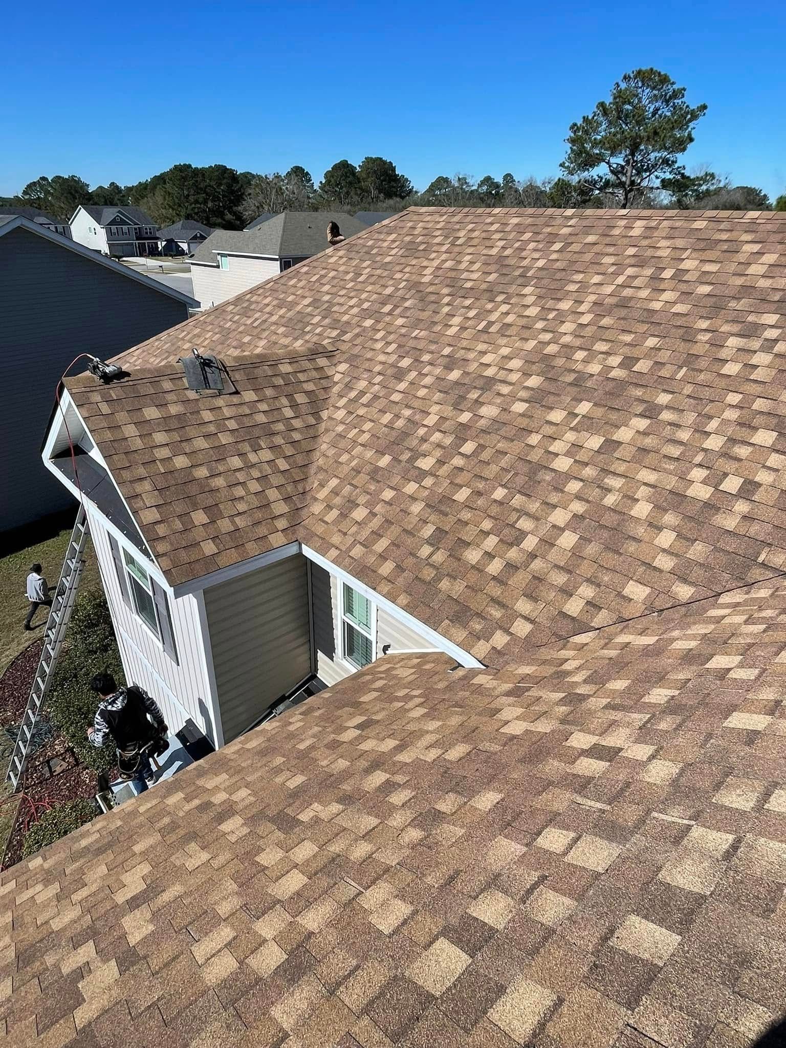 Brown shingled roof of a house under a clear, blue sky.