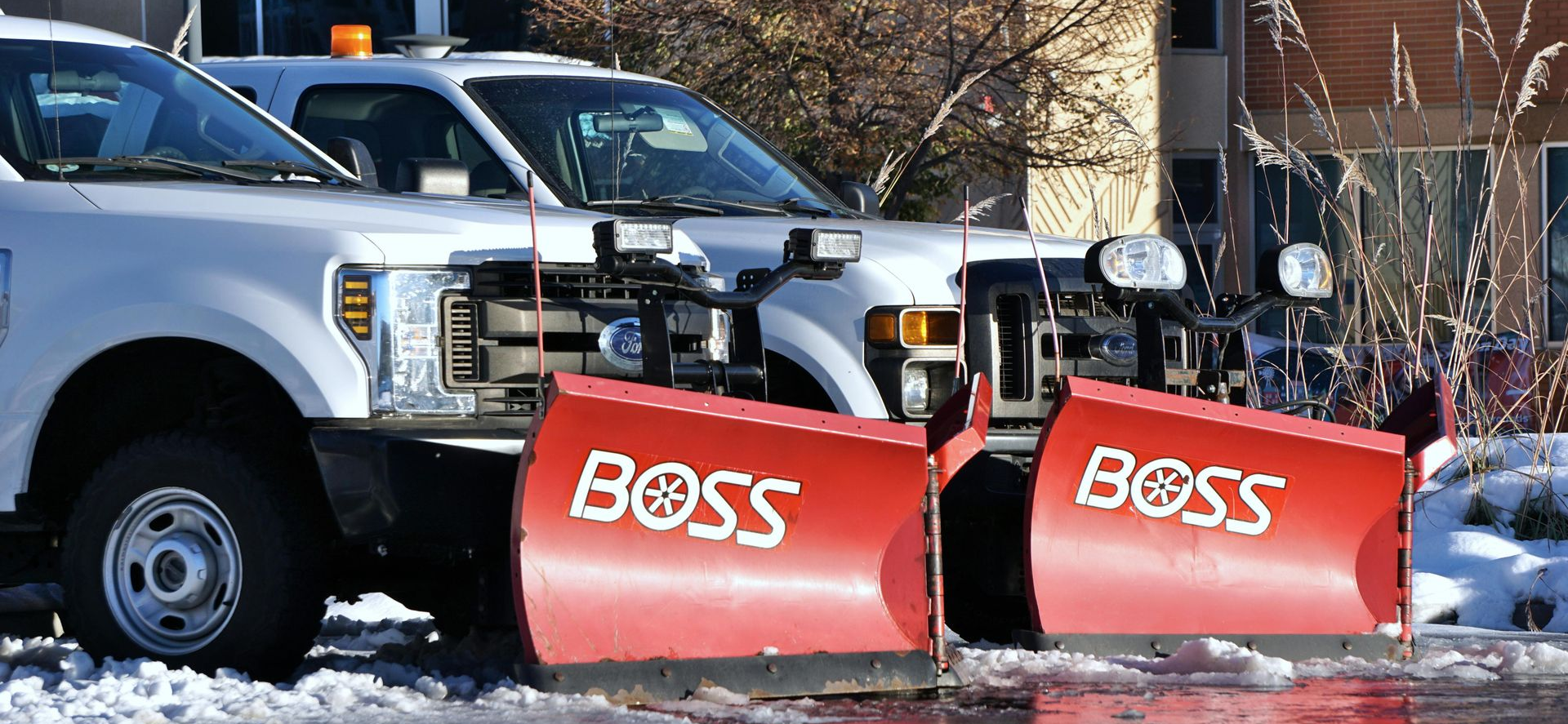 Snow plow truck clearing snow from a road on a cloudy day.