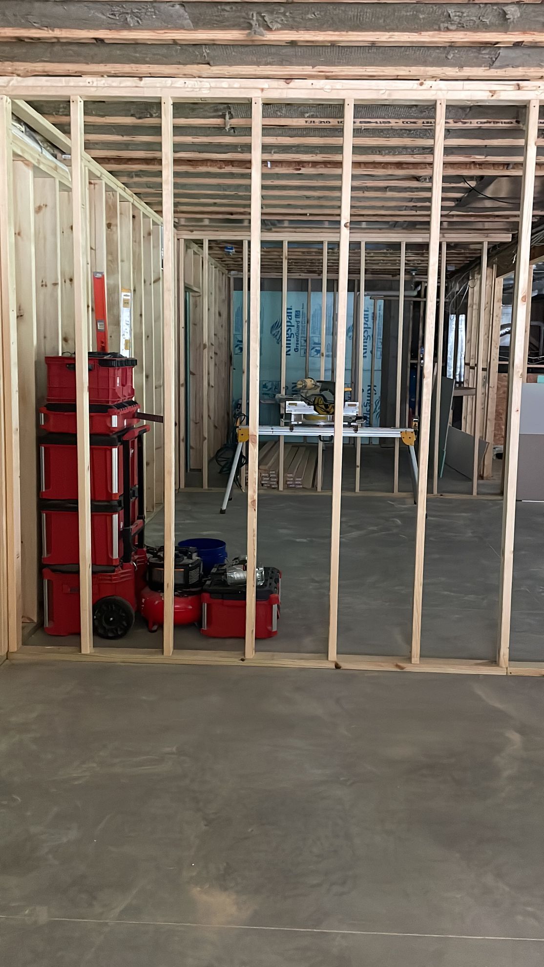 A concrete patio next to a house, surrounded by landscaping and a gazebo in the backyard.