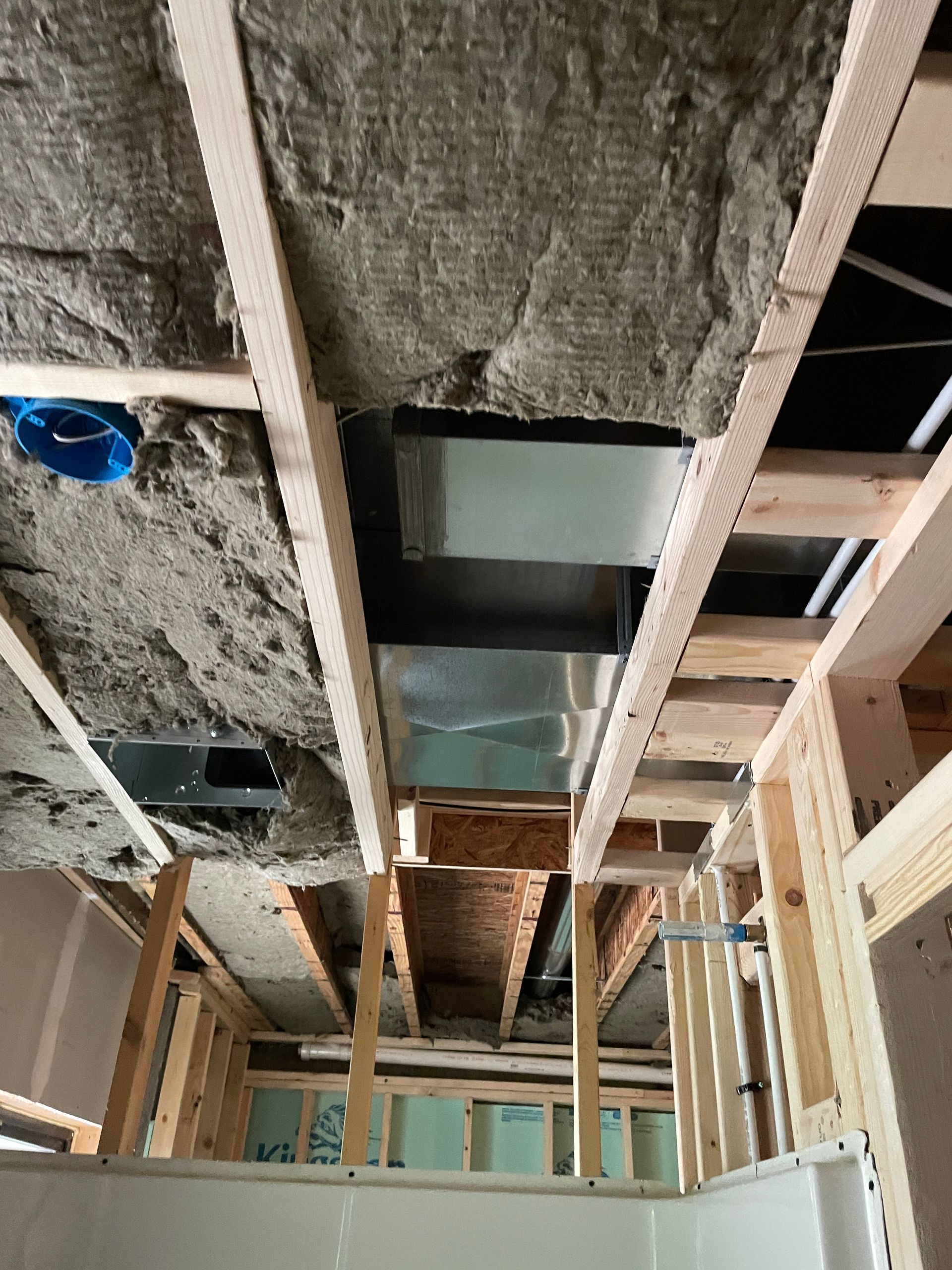 New wooden porch being built on a white house.  Shingles on roof and green grass.