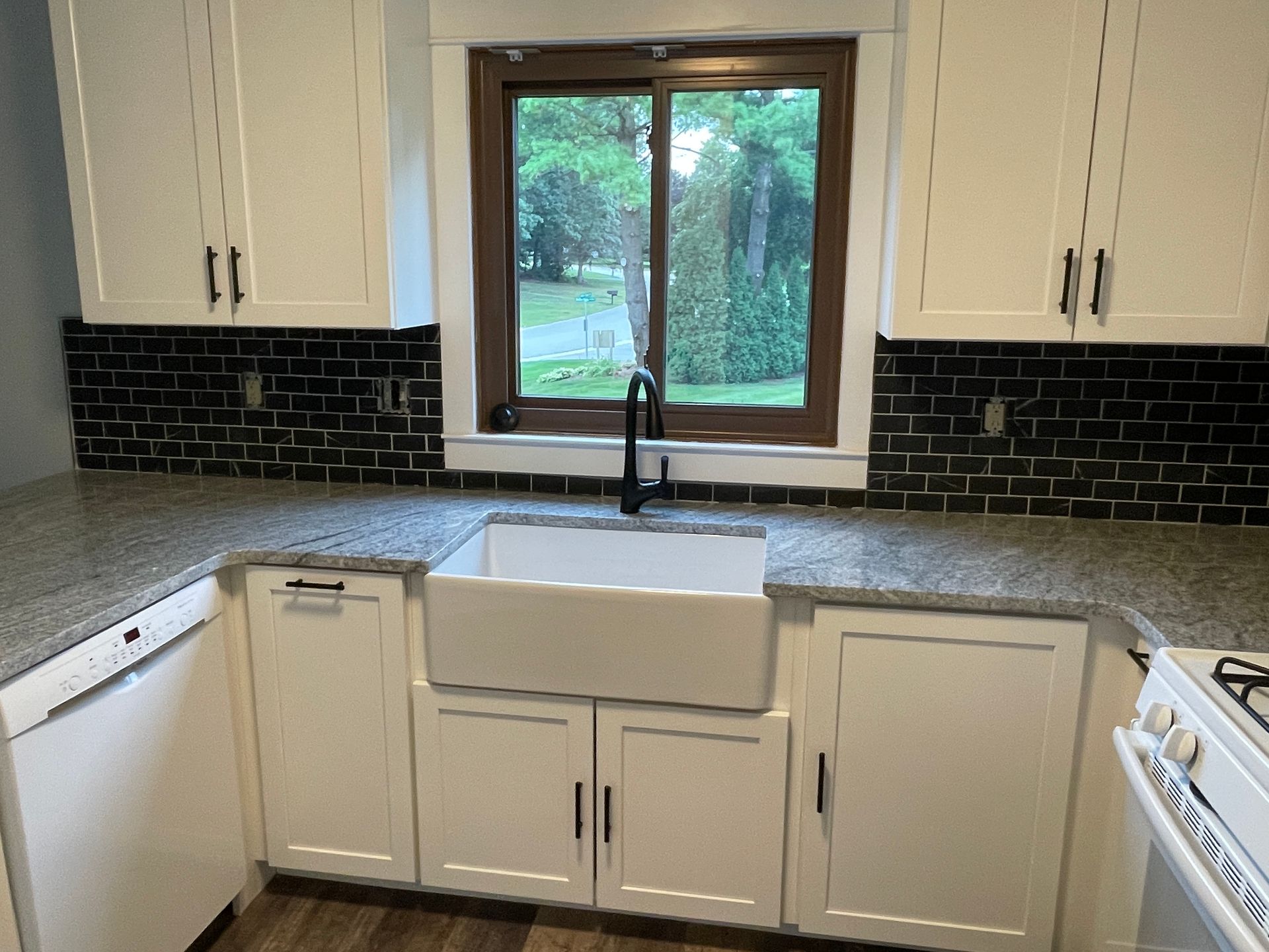 Interior wall under construction, exposing insulation, wiring, and wooden studs. A doorway is visible in the background.