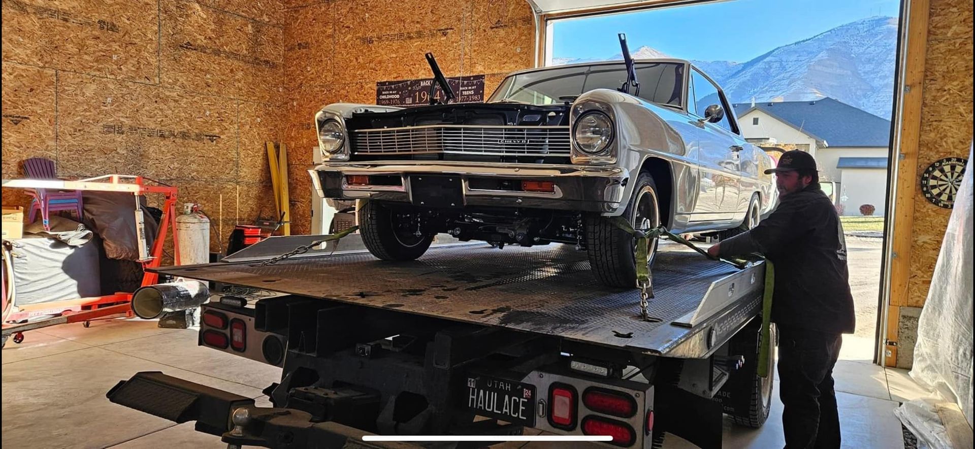 A man is loading a car onto a tow truck in a garage. A man is loading a car onto a tow truck in a garage.