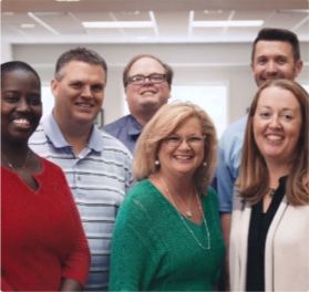A group of people are posing for a picture and one woman is wearing a green shirt