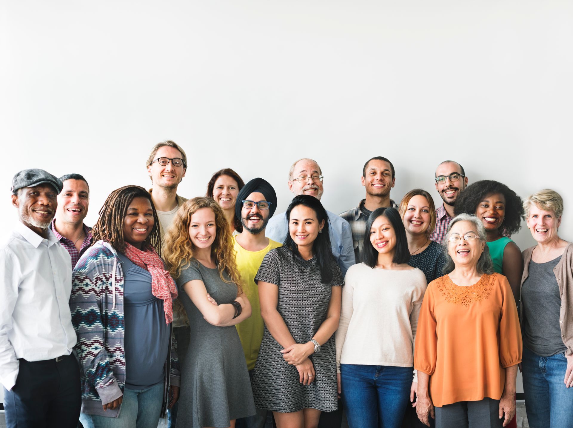Group of diverse people smiling, standing in front of a white wall.