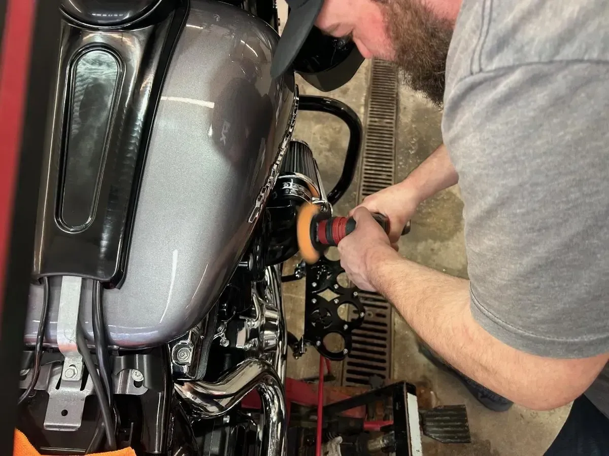 Mechanic using a power tool on a motorcycle in a workshop