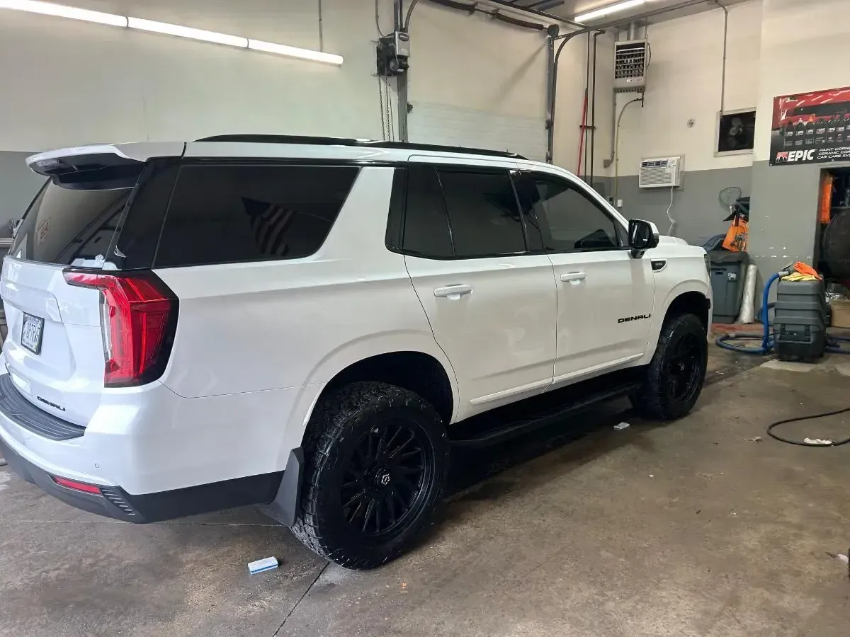 White SUV with black rims parked inside an auto shop garage