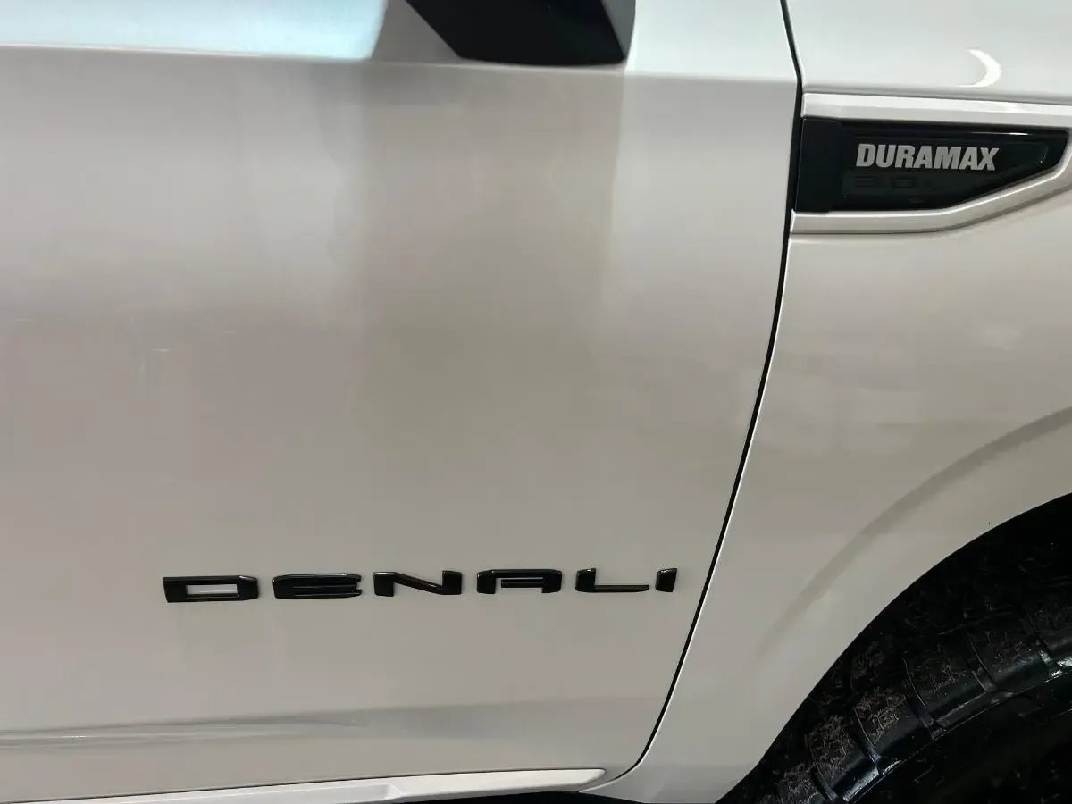 Close-up of a silver Chevrolet Duramax Denali truck door and front fender badge.