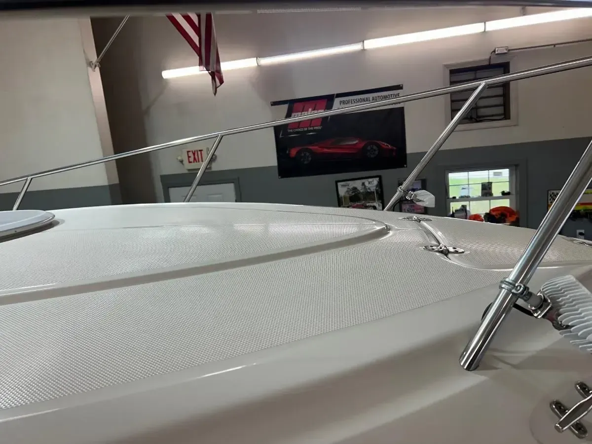 White boat docked indoors, showing the deck, windshield, and speaker on the side.