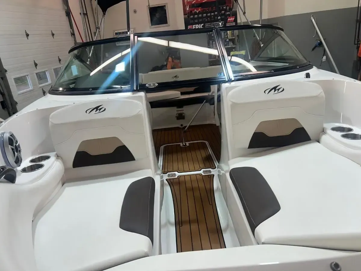 White boat interior with twin seats, teak floor, and windshield in a workshop гараж