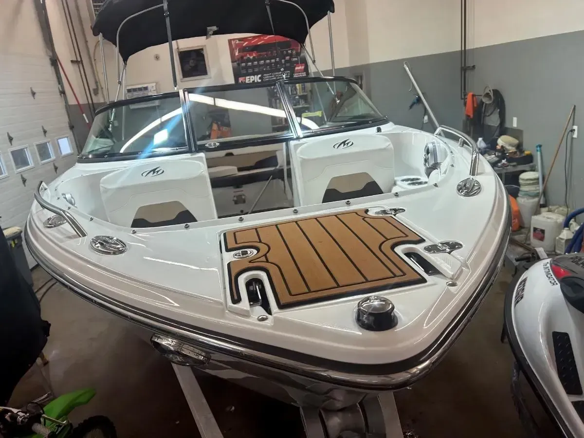 White boat with tan wood-style deck trim inside a workshop or garage