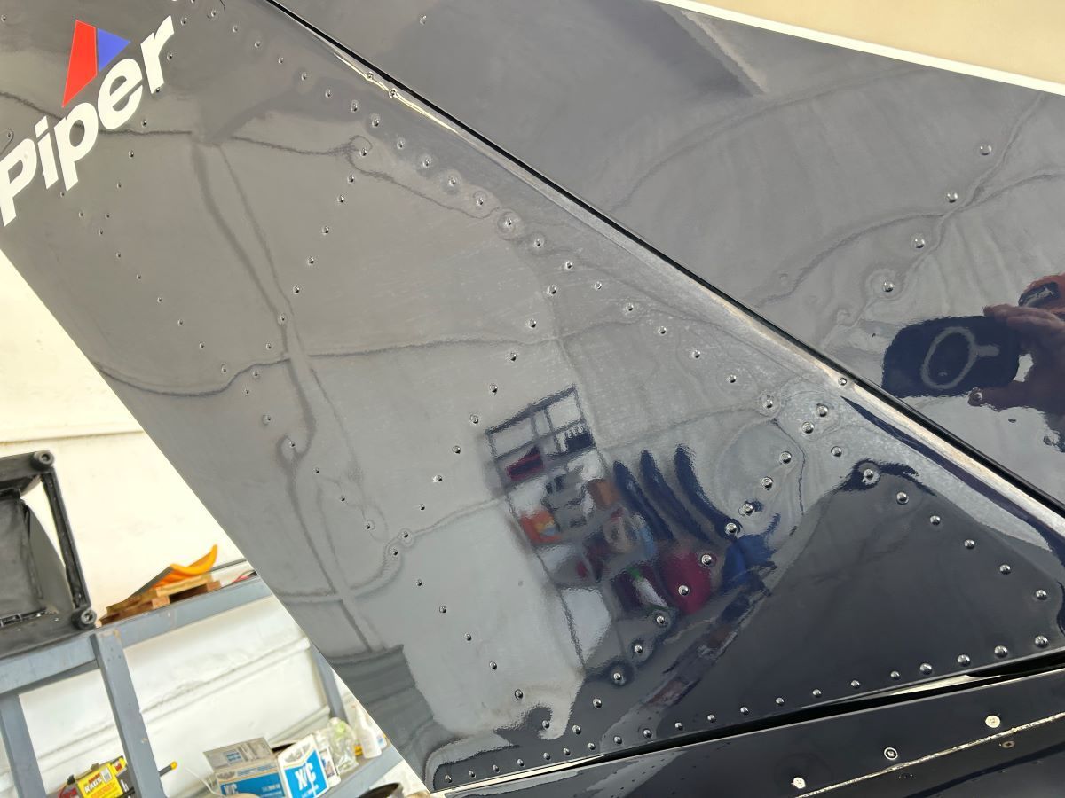 A black piper plane is sitting in a garage