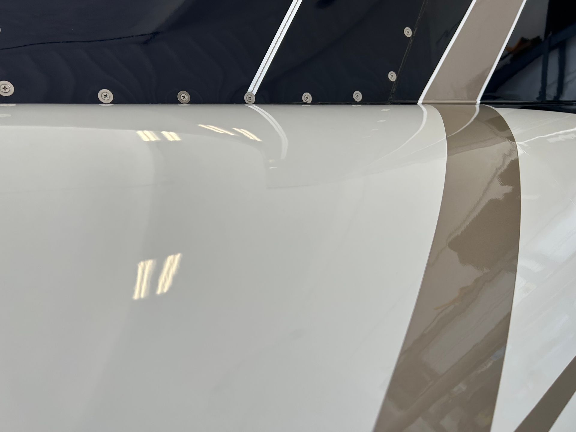 A close up of a white vehicle with a brown stripe on the side