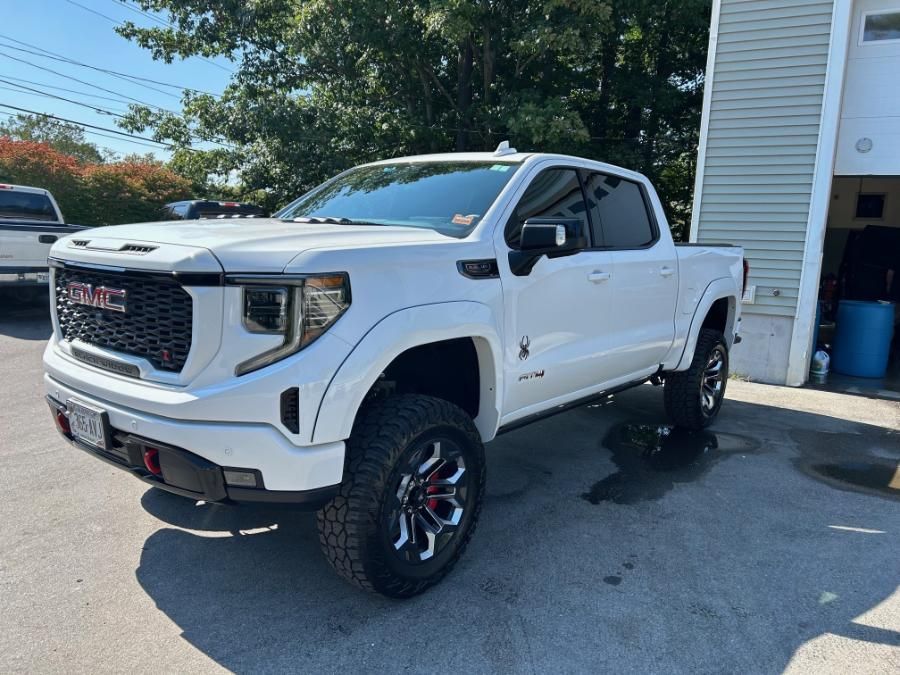 A white gmc truck is parked in front of a garage.