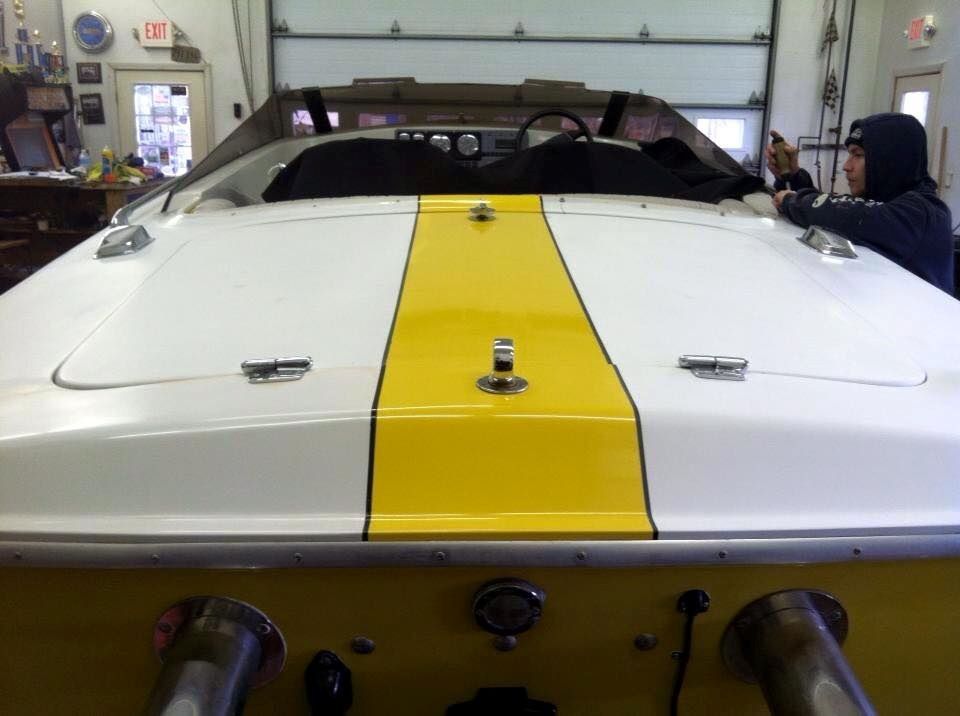 A man taking a picture of a yellow and white boat