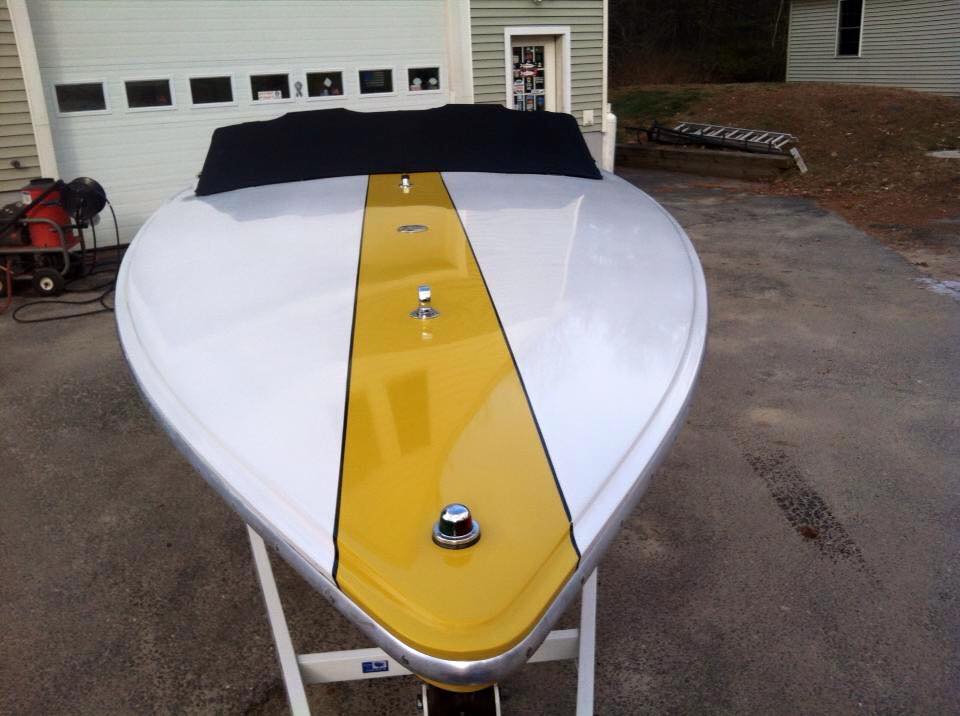 A white and yellow boat is parked in front of a garage door