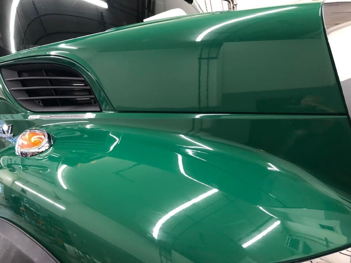A green golf cart is parked in a garage.