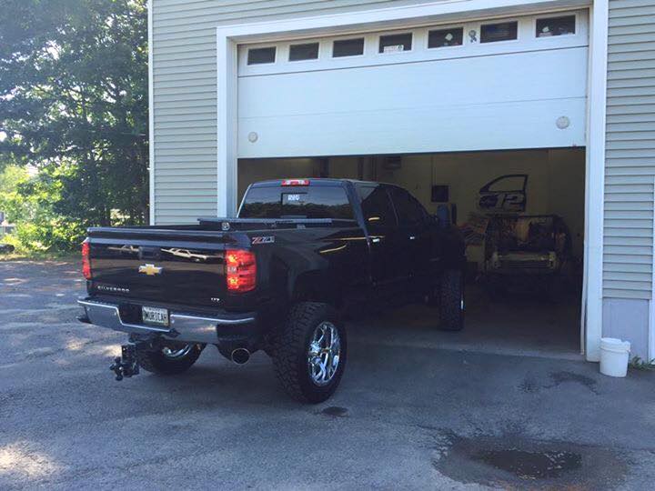 A black truck is parked in a garage with the door open