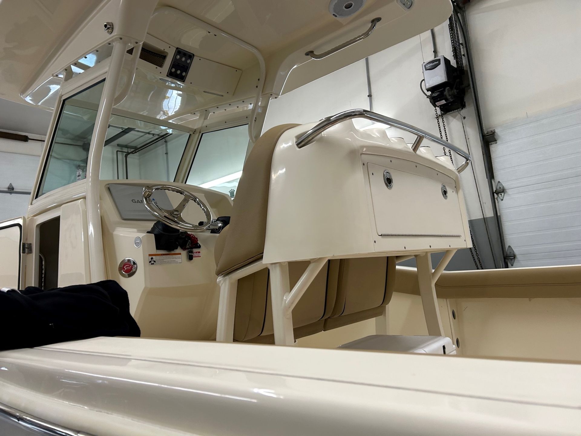 A person is sitting in the cockpit of a boat in a garage.