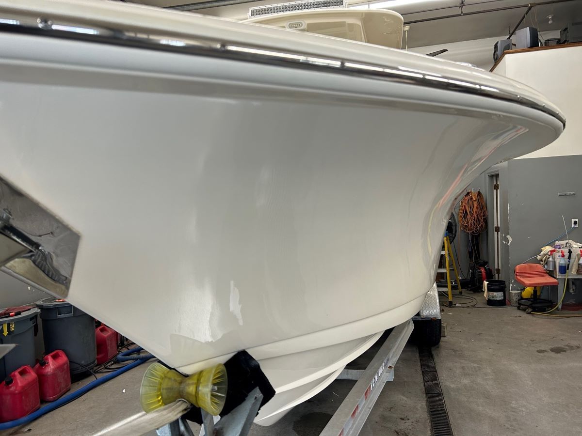 A white boat is sitting on a trailer in a garage.