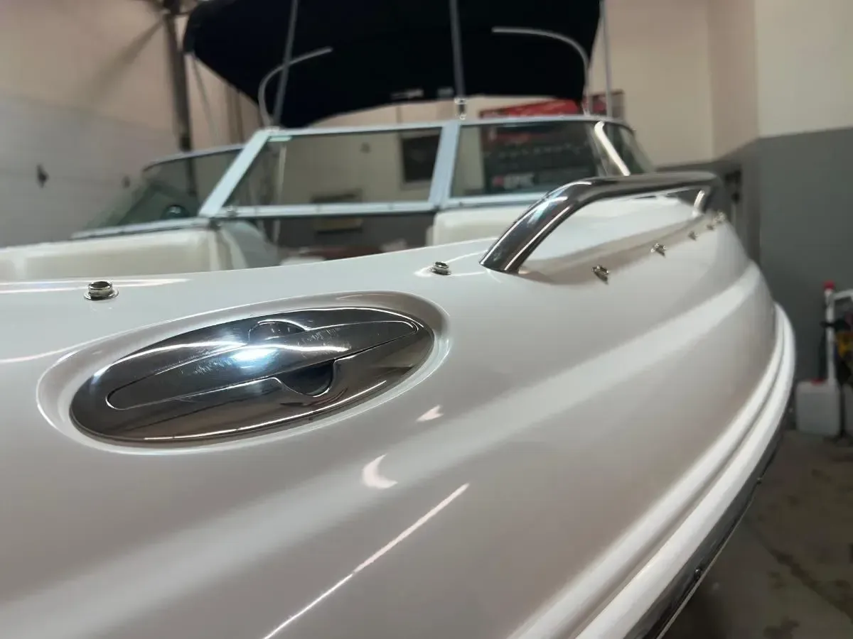 Close-up of a white boat's polished bow with chrome details, including a rail and a large oval light.