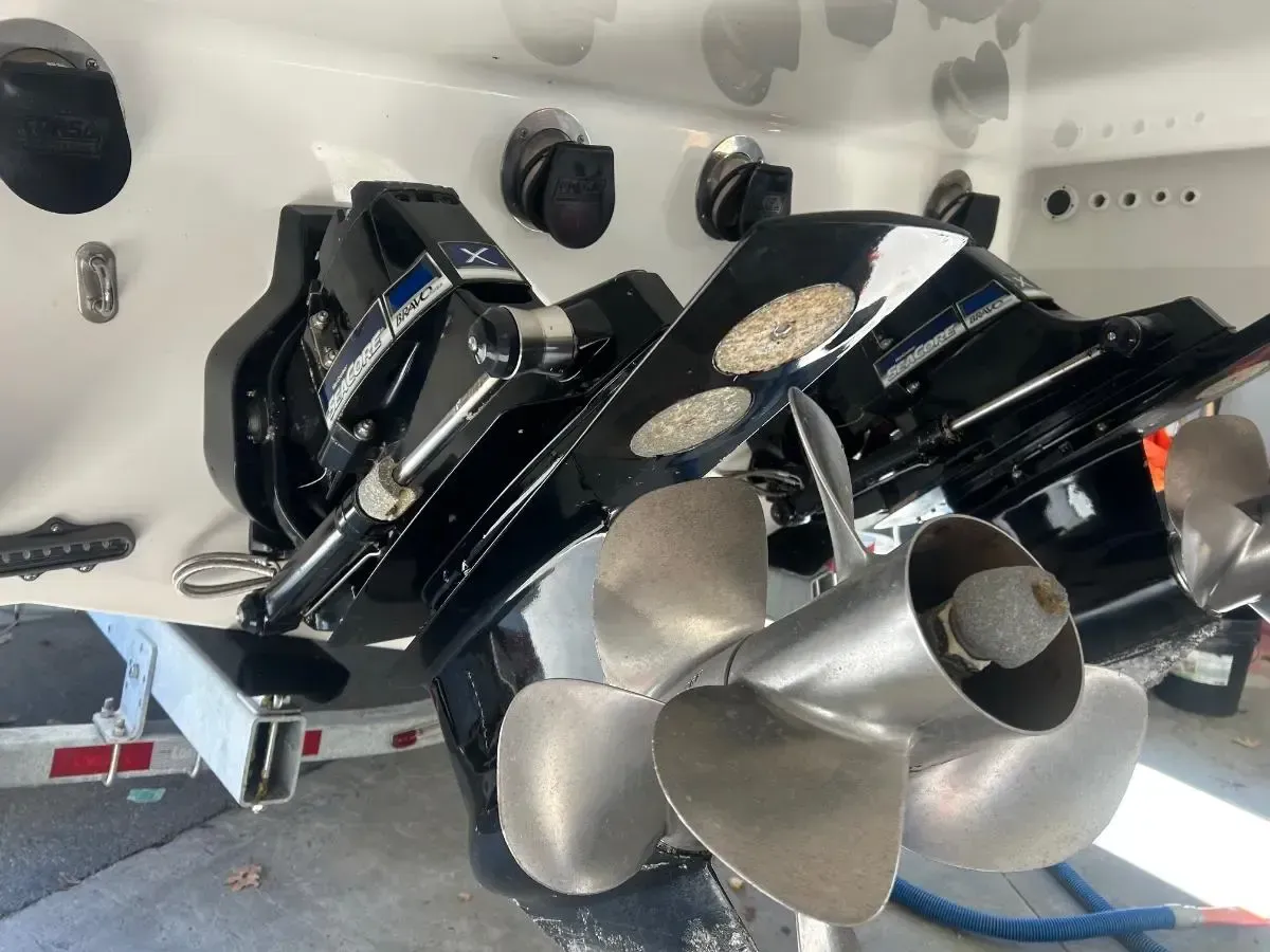 Two black boat engines with propellers, mounted on a white boat hull, angled view.