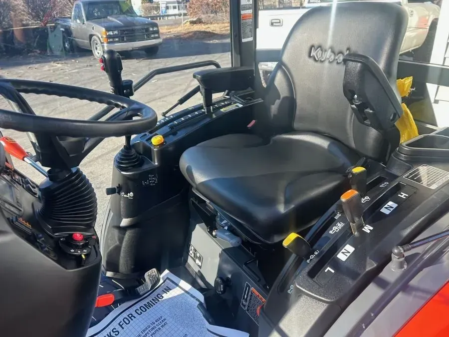 Interior of Kubota tractor with black seat, controls, and steering wheel.