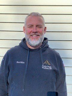 A man with a beard is wearing a hoodie and smiling.