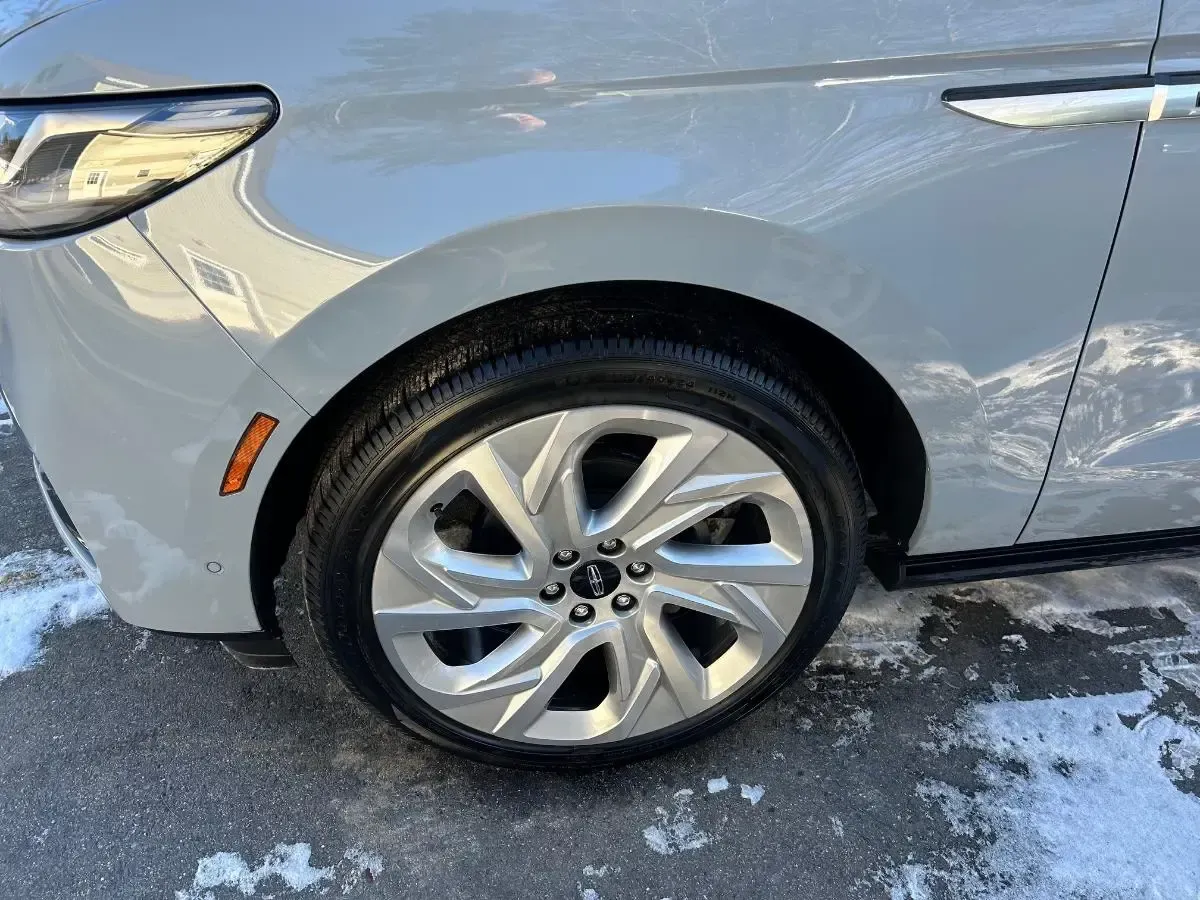 Silver car wheel and fender on a snowy surface.