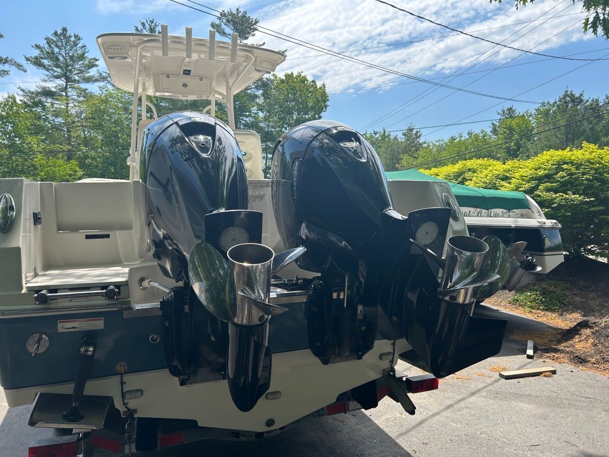 A boat with two outboard motors is parked in a driveway.